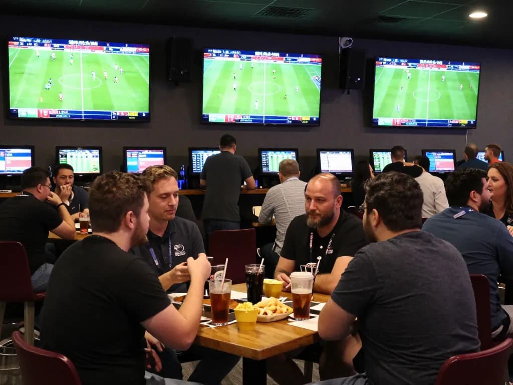 Engaged fans exploring trang cá cược bóng đá at a lively sports betting venue during a live match